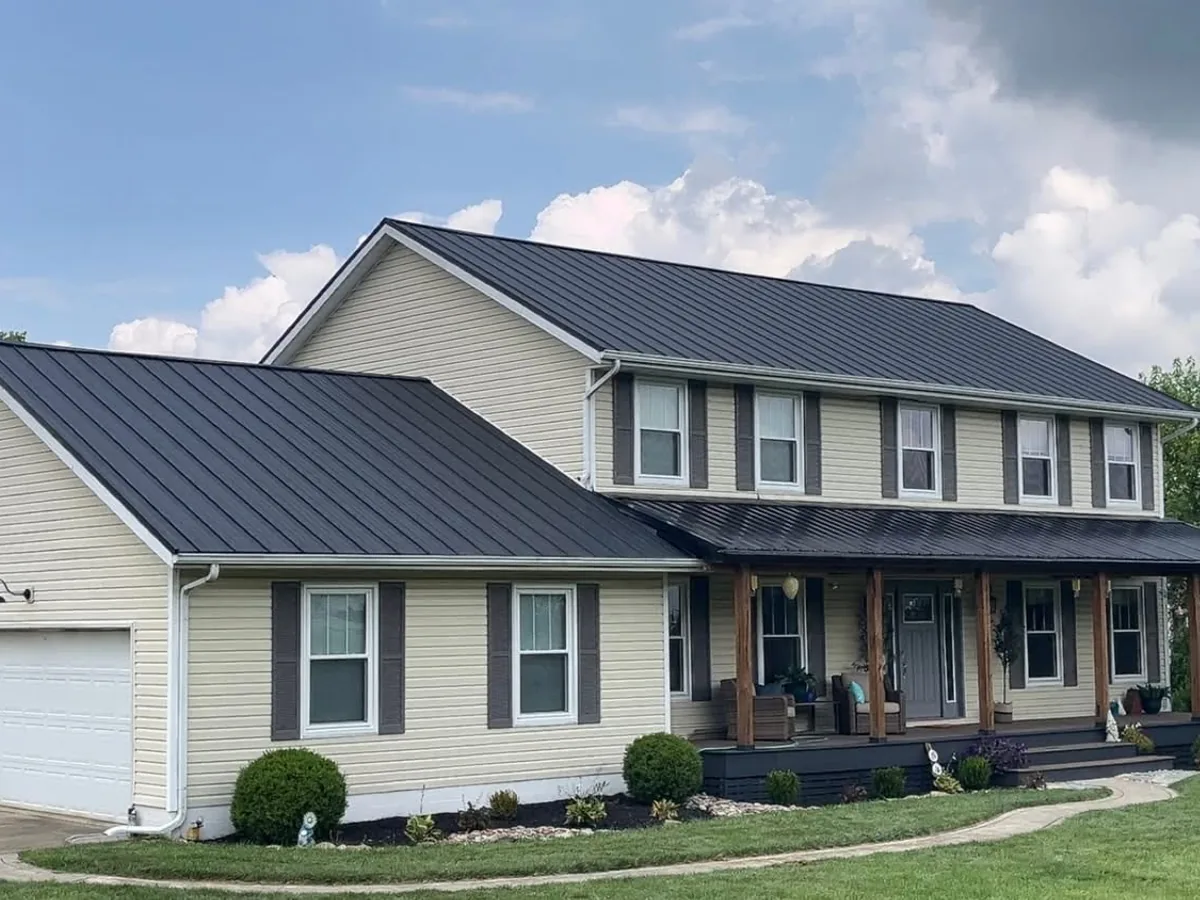 Two-story home with dark metal roofing across the main roof, garage, and porch